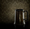 Old pewter drinking mug, tankard. With back lighting and old dam Royalty Free Stock Photo
