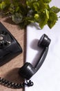 Old phone on wooden table with white tablecloth and artificial green plants. Black antique on a table Royalty Free Stock Photo