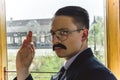 old photo of man in suit with a mustache and glasses on the train showing sign ok with hand Royalty Free Stock Photo
