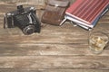 Old photocamera with leather case, notebooks on vintage wood background Royalty Free Stock Photo
