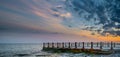 Old pier on background of sunset on beach