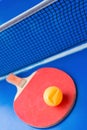 Old pingpong racket and a dented ball on blue pingpong table