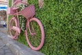 Old pink basket bike standing on pavement. It& x27;s attached to the wall Royalty Free Stock Photo