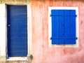 Old pink painted building with blue door and blue window shutters Royalty Free Stock Photo