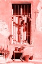 Old pink painted house with cracked walls, wooden window and plants in trendy coral color. Pop art concept, retro style