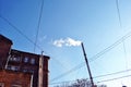 Old pipe with smoke, red brick building corner with windows and wires on winter bright blue sky background, view from ground Royalty Free Stock Photo