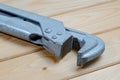 Old pipe wrench on a wooden background. Plumber adjustable wrench