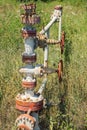 Old pipes and valves used to pump oil from oil rigs abandoned in the field. The pipes have rust and peeling paint