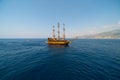 Old pirate ship on the water of Mediteranean sea. Tourist entertainment, coastal tour. Summer sunny day. Mountain shore of Alanya