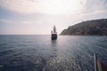 Old pirate ship on the water of Mediteranean sea. Tourist entertainment, coastal tour. Summer sunny day. Mountain shore of Alanya