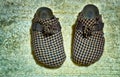 Old plaid worn slippers on an old carpet