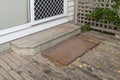 Old plain coir doormat placing in front of the doorstep