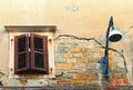 Old plaster fell off and a brick wall is visible. Window with closed wooden shutters near modern diode lantern. Royalty Free Stock Photo