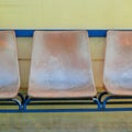 Old plastic seats on outdoor stadium players bench, chairs with worn paint Royalty Free Stock Photo