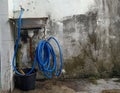 An old plastic water faucet with a blue water hose Royalty Free Stock Photo