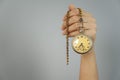 Old pocket watch in a female hand on a gray background