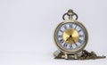 The old pocket watch is a necklace located on the white floor being separated