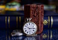 Old pocket watch and books on a mirror surface Royalty Free Stock Photo