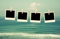 Old polaroid photo frames hanging on a rope with beach background Royalty Free Stock Photo