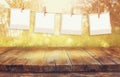 Old polaroid photo frames hanging on a rope with vintage wooden board table in front of abstract forest landscape Royalty Free Stock Photo