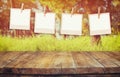 Old polaroid photo frames hanging on a rope with vintage wooden board table in front of abstract forest landscape Royalty Free Stock Photo