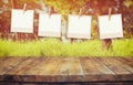 Old polaroid photo frames hanging on a rope with vintage wooden board table in front of abstract forest landscape