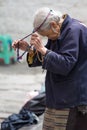 Old and poor Tibetan woman during her religious ceremony