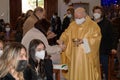 Old priest is distributing communion host to the faithful during a mass in the period of coronavirus. people wearing a protective