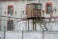 Old prison wall with barbed wire and observation tower behind it. Royalty Free Stock Photo