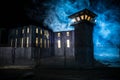 Old prison watchtower protected by wire of prison fence at night. Creative art decoration. Selective focus Royalty Free Stock Photo