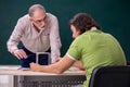 Old professor physicist and young student in the classroom