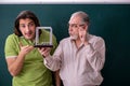 Old professor physicist and young student in the classroom