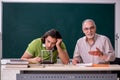 Old professor physicist and young student in the classroom