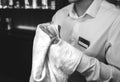 Old pub with bartender cleaning the glass with white towel on background. Empty name tag badge on the shirt uniform. Barman at his Royalty Free Stock Photo