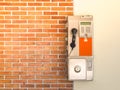 An old public payphone with red brick wall. Royalty Free Stock Photo