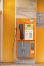 Old public phone booth orange color for coins Royalty Free Stock Photo