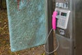 Old public telephone made of silver metal with pink telephone receiver Royalty Free Stock Photo