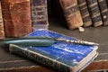 Old quill pen, books and vintage inkwell on wooden desk in the old office against the background of the bookcase and the