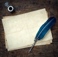 Old quill pen, and old paper blank sheet and vintage inkwell on wooden desk in the old office . Retro style. Conceptual background Royalty Free Stock Photo