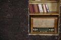 Old radio and books on a shelf against brown brick wall Royalty Free Stock Photo