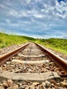 Old railroad surrounded by bright green grass under a sunny sky full of clouds Royalty Free Stock Photo