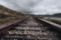 Old railroad with wooden ties and gravel ballast on a rocky hill against a cloudy sky Royalty Free Stock Photo
