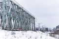 Old railway bridge across the river covered with snow in winter. Railway power lines Royalty Free Stock Photo