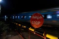 Old railway in India, Kerala. Rusty Stop sign, long train with cars, railway crossing barrier Royalty Free Stock Photo