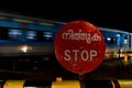 Old railway in India, Kerala. Rusty Stop sign, long train with cars, railway crossing barrier Royalty Free Stock Photo