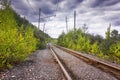 Old railway line in the mountains. Part of the old railway and old power line support near the forest and mountains Royalty Free Stock Photo