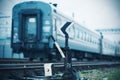 An old railway switch stands against the background of rails on which a  train leaves in cloudy sad weather Royalty Free Stock Photo