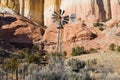 Old ranch windmill and fence in front of colorful high cliffs in the desert landscape of the American Southwest Royalty Free Stock Photo