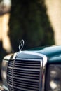 Old rare vintage green Mercedes-Benz hood, badge, glasses, headlights, radiator grille on blurred background