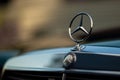 Old rare vintage green Mercedes-Benz hood, badge, radiator grille on blurred background. The symbol of rich life.